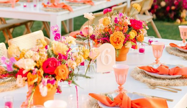 Decoraciones de mesa en color rosa brillante con tonos cítricos que son perfectas para una boda de verano